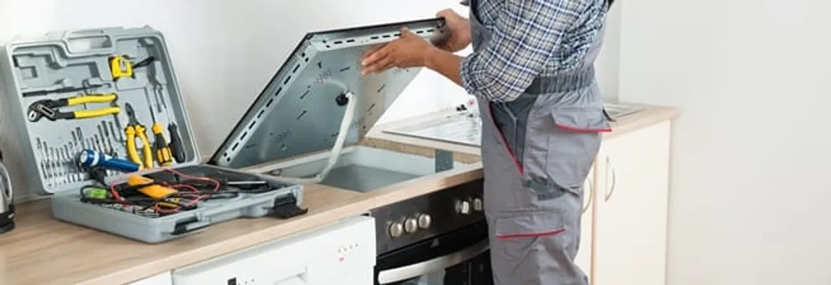 Cooktop repair technician lifting a built-in stovetop for service in Salt Lake City, UT