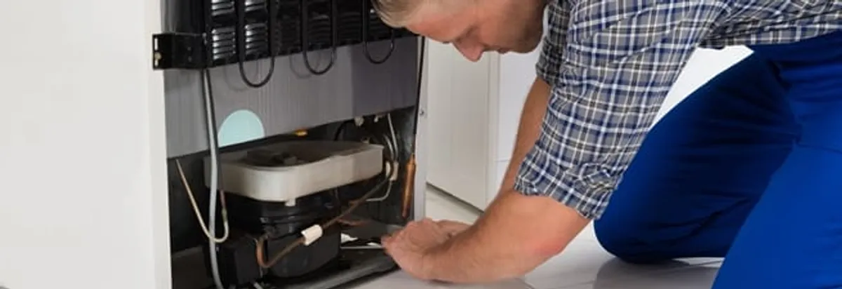 Refrigerator repair technician servicing the compressor and condenser area in Salt Lake City, UT
