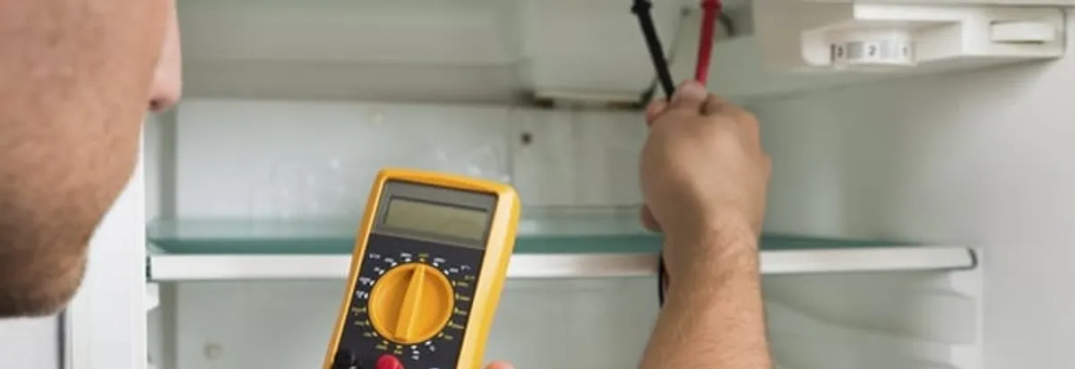 Refrigerator repair technician testing electrical components with a multimeter in Salt Lake City, UT