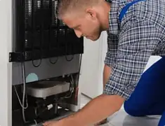 Refrigerator repair technician servicing the compressor and condenser area in Salt Lake City, UT