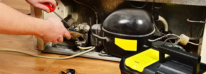 Refrigerator repair technician fixing the compressor and wiring in Salt Lake City, UT